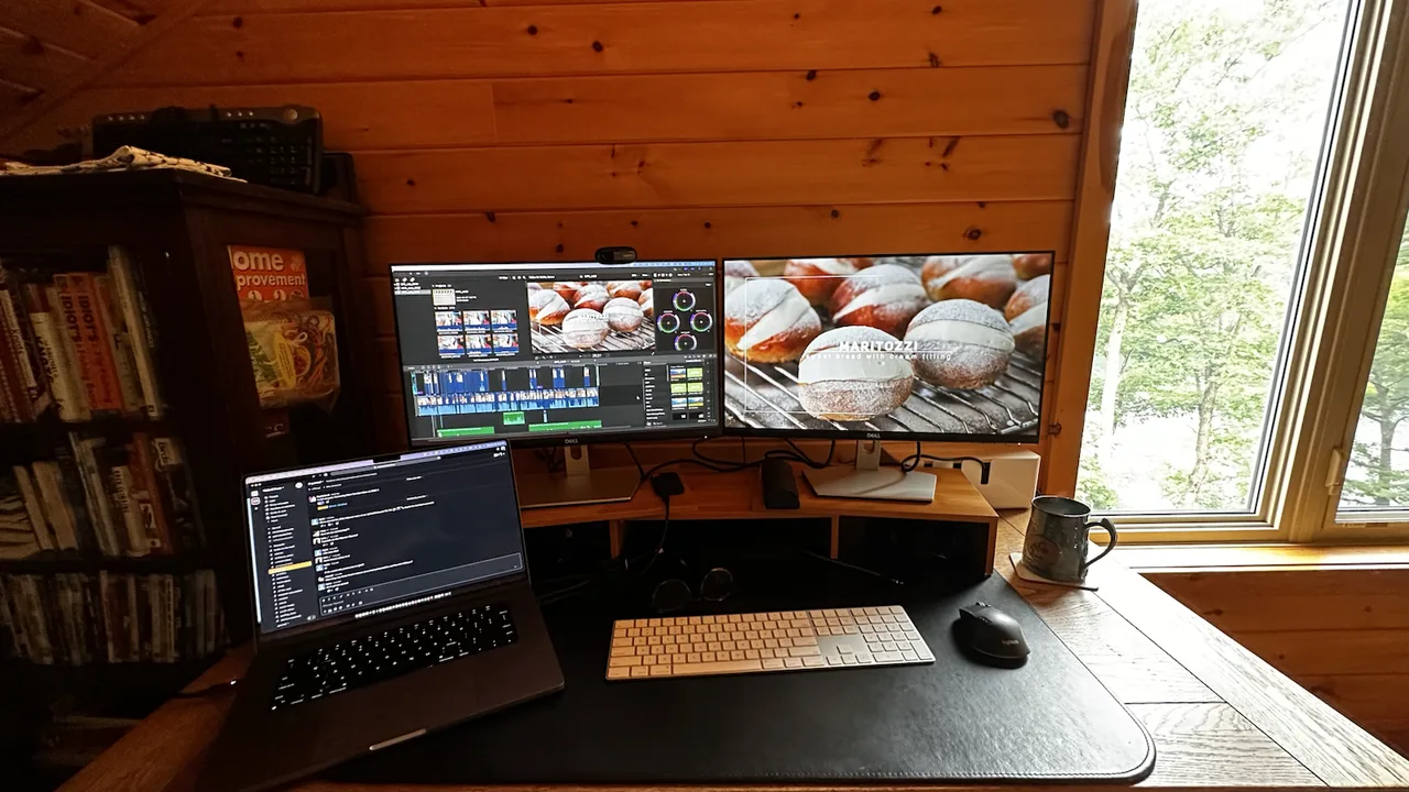 Laptop and monitors at an editing workstation by a window