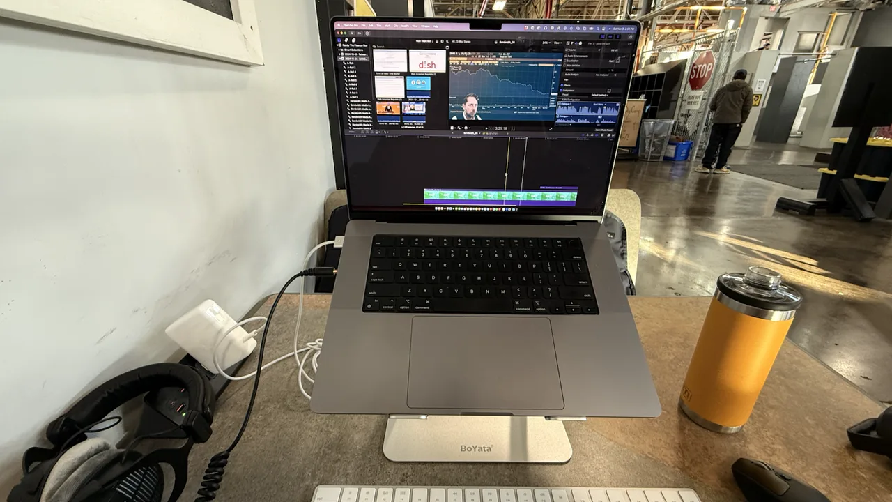 Laptop editing station with headphones on a production floor